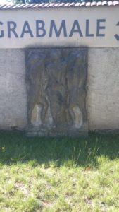 Das Relief, das an der Friedhofsmauer lehnt. Es war wohl mal Teil eines Grabes. Möglicherweise ist es die Darstellung der Schicksalsgöttinnen (Moiren/Parzen). Aber wer weiß.