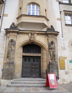 Über dem Eingangsportal hängt den Schlussstein markierend die Stadtpatronin Doblina, die das Stadtwappen trägt. Die Männerfiguren rechts und links des Eingangs sollen  Klugheit und Tatkraft darstellen.